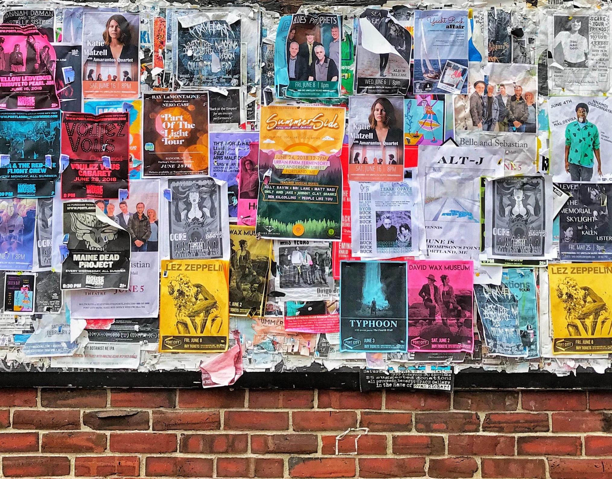 Image of several posters on a brick wall