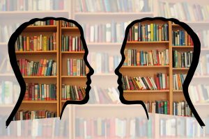 Two clear silhouettes facing each other in front of bookshelves with muted colours around the silhouettes.