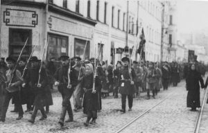 In this photograph, we see Bolshevik militia, men and women alike, walking on a street in Moscow.