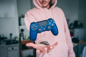 person in a pink hoodie tossing a gaming console in the air