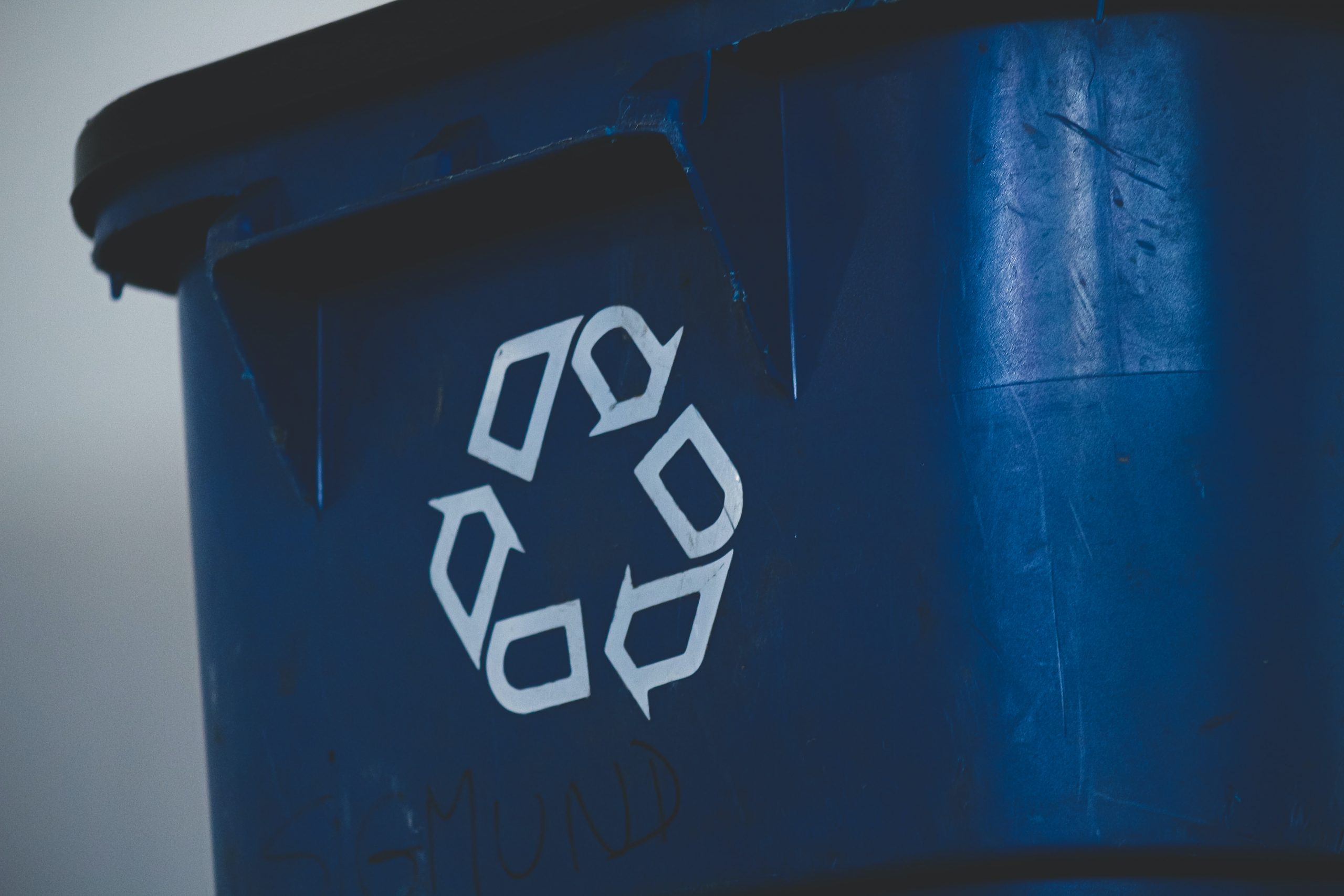Image of a blue plastic bin (showing the recyclye logo) that is typically used for recycling used containers.