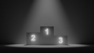Image of 3 podiums representing 1st place, 2nd place, 3rd place, against a dark background.