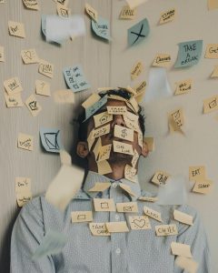 Person leaning against a wall with post-it notes all over his face and the wall representing decision confusion.