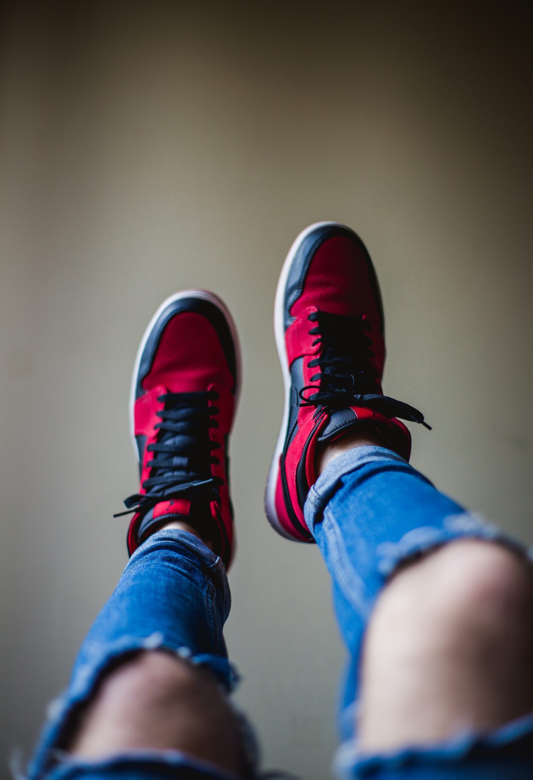 Pair of Air Jordan sneakers worn on a person with trendy looking ripped jeans.