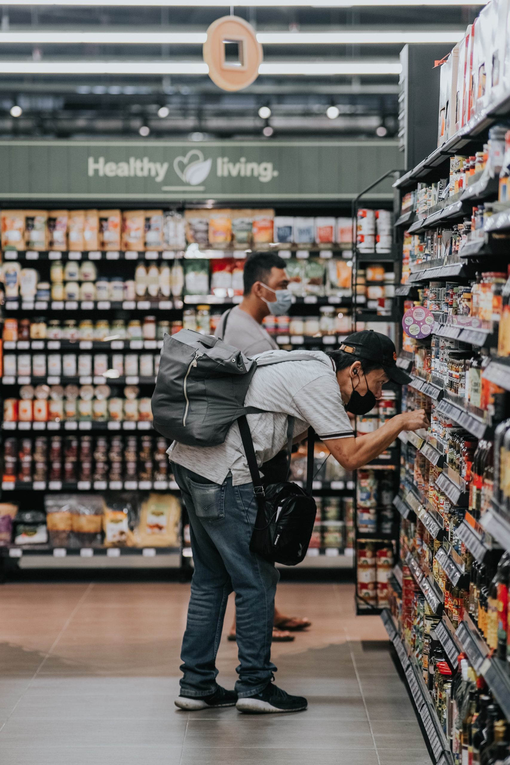 Two men shopping in a grocery store while maintaining social distancing and wearing masks.
