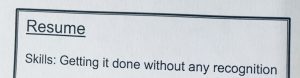 "A piece of paper with the word 'resume' printed in bold at the top, and underneath that the words 'Skills: getting it done without any recognition' are printed."