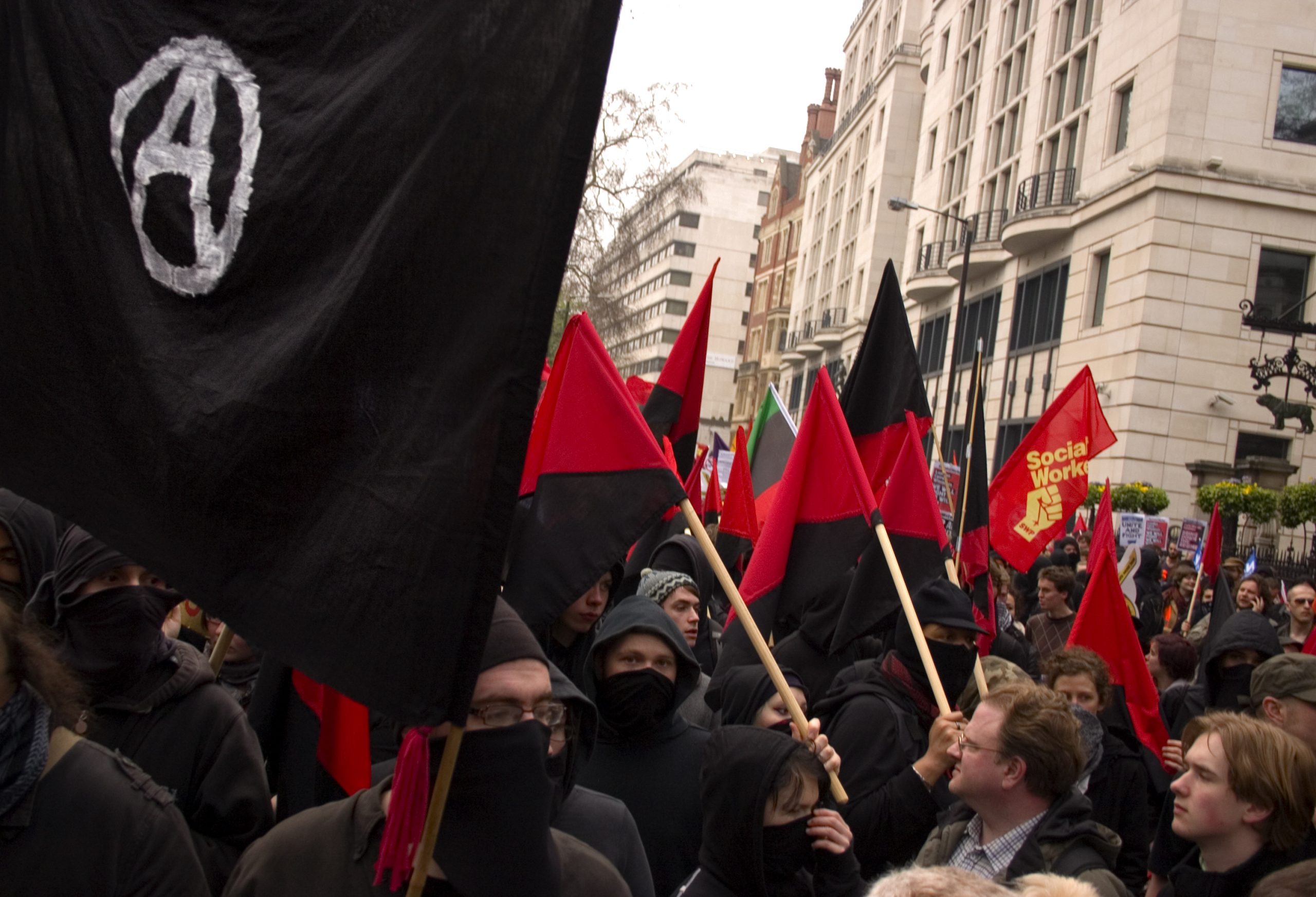 Protest featuring anarchist and socialist flags.
