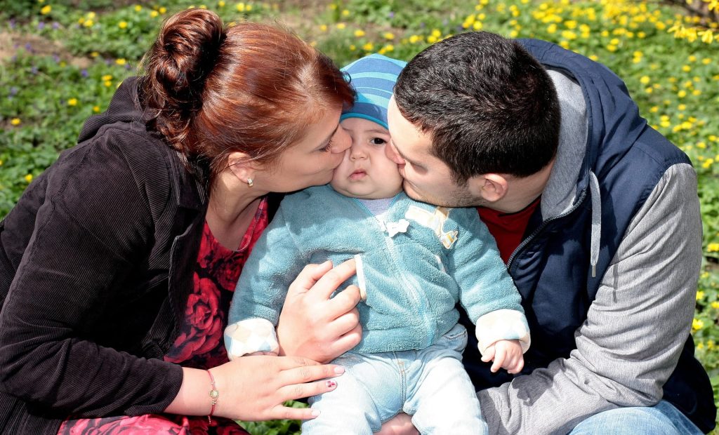 Parents kissing their child.