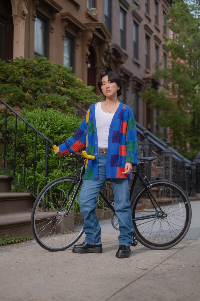 A non-binary person standing with their bike