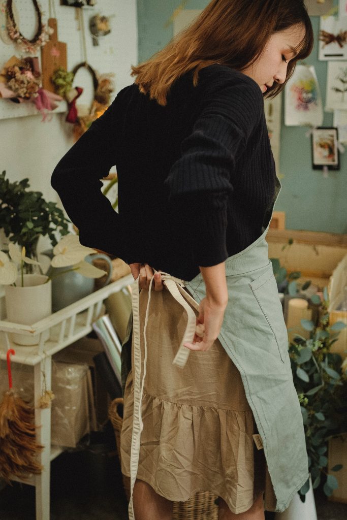 A young lady tying her apron in a flower shop