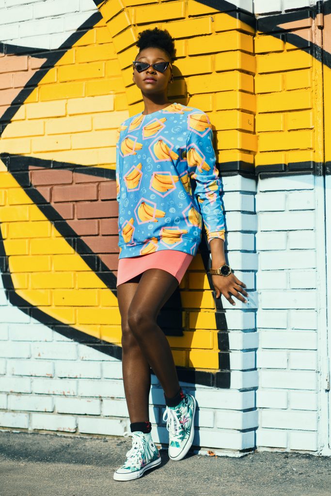 A woman wearing colourful clothing stands against a background.