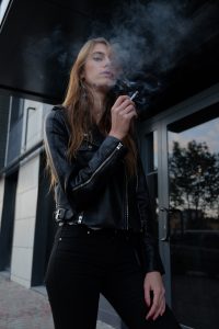woman wearing leather jacket smoking a cigarette