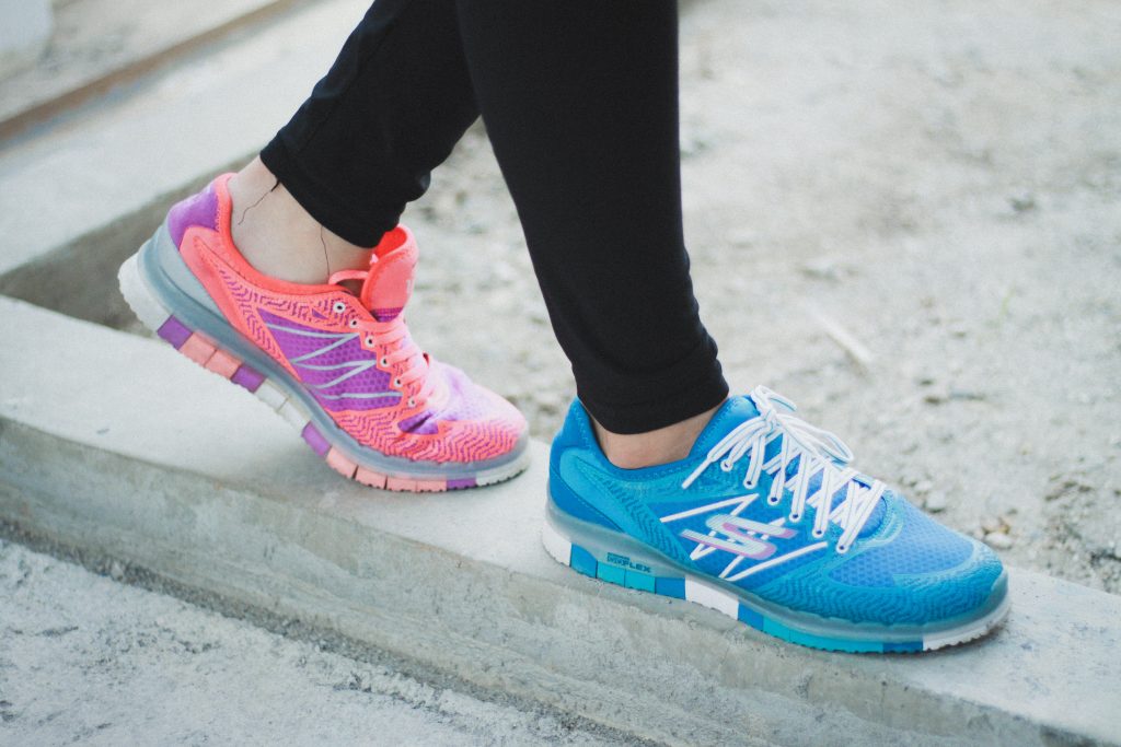 Person's feet, wearing two different coloured sneakers reflecting a consumer's unique personal preference.